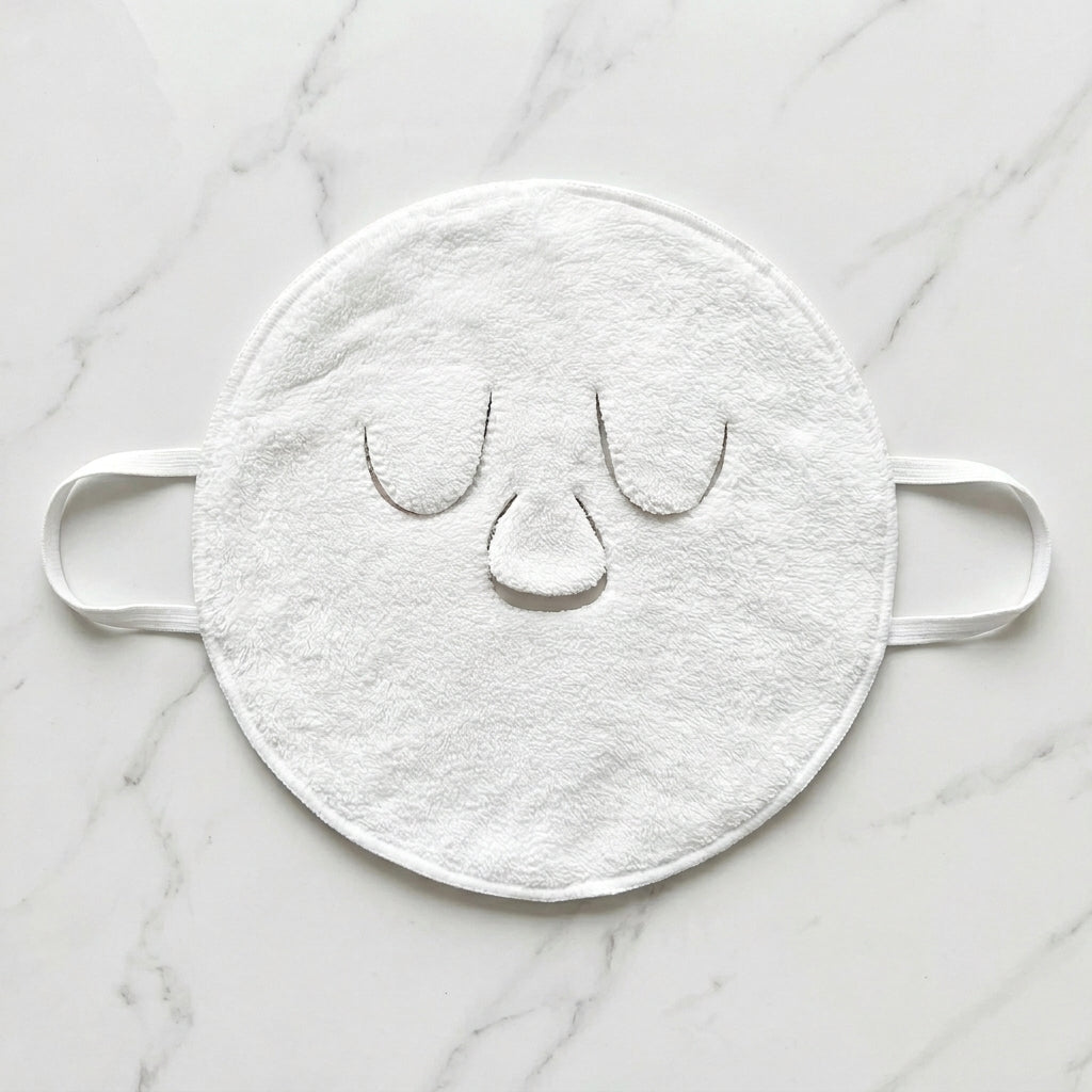 Soma cotton facial hot compress laid flat on marble, showing the eye and nose openings and ear loops